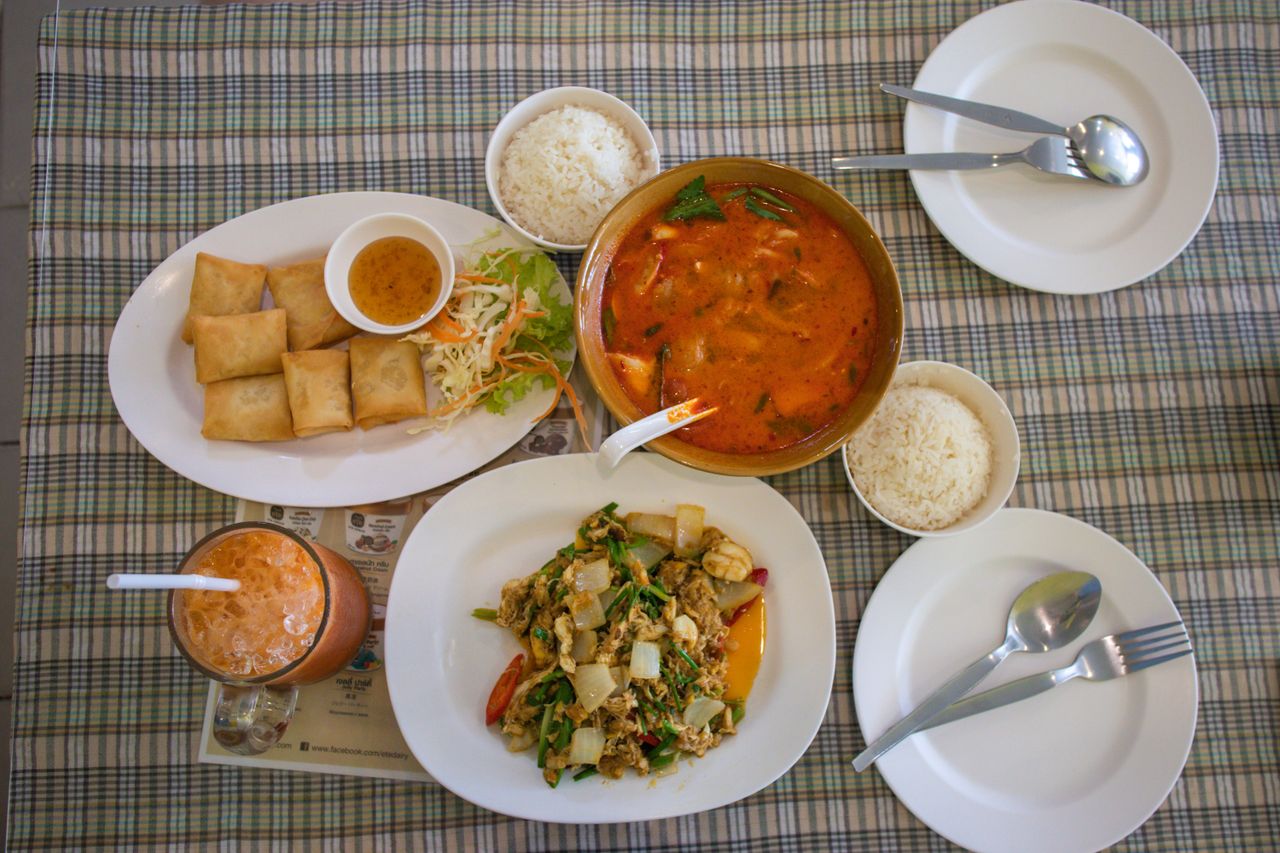 heros-img Top view of a traditional Thai meal with curry, rice, and spring rolls on a table.